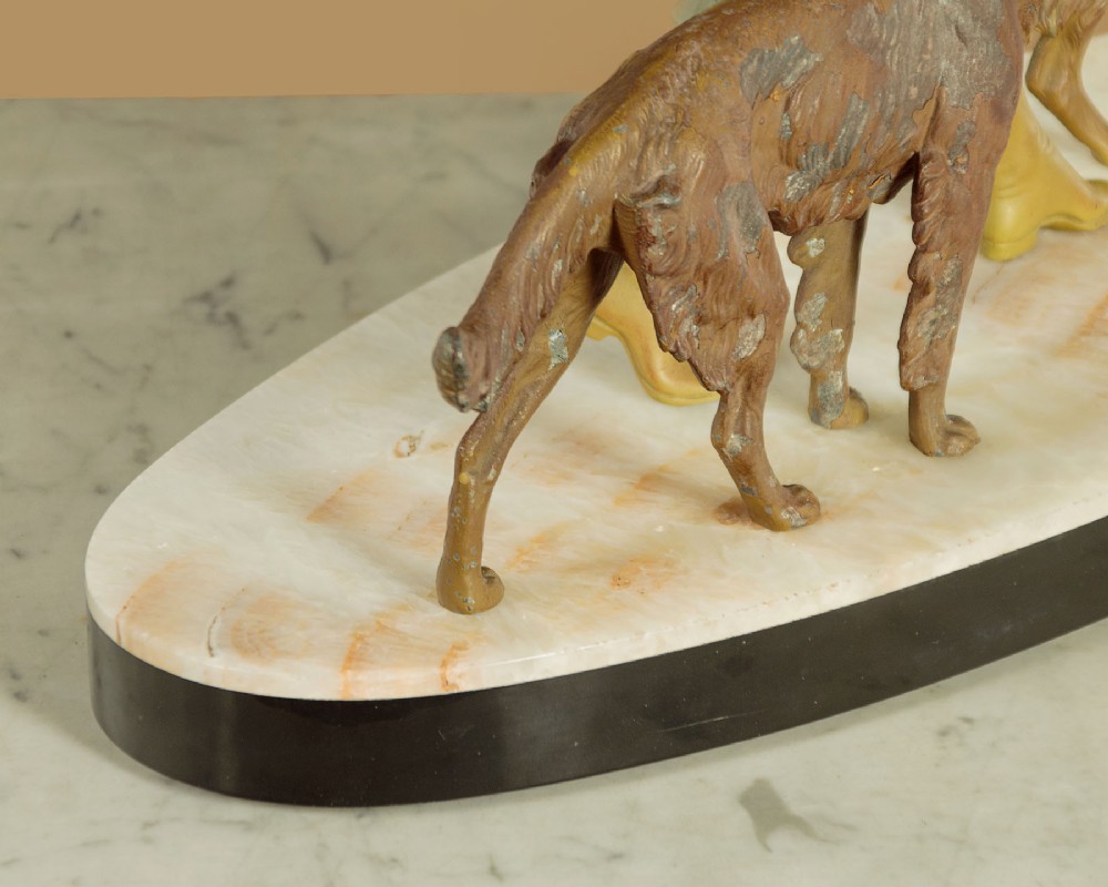 Art Deco figure group depicting a huntress in a green suit with two hunting dogs mounted on an oval marble base. View XIV