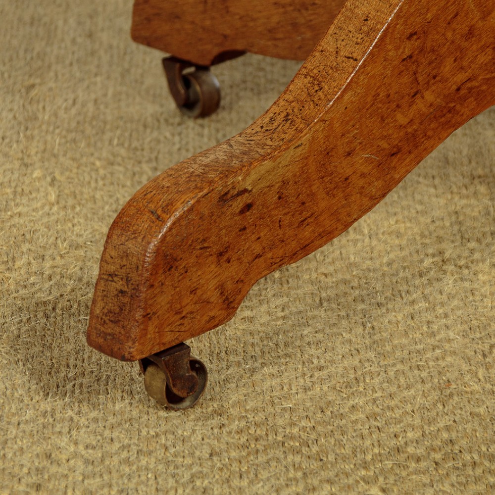 An early twentieth-century solid oak revolving desk chair featuring a slatted backrest, curved armrests, and a quadruped base on castors. View XI