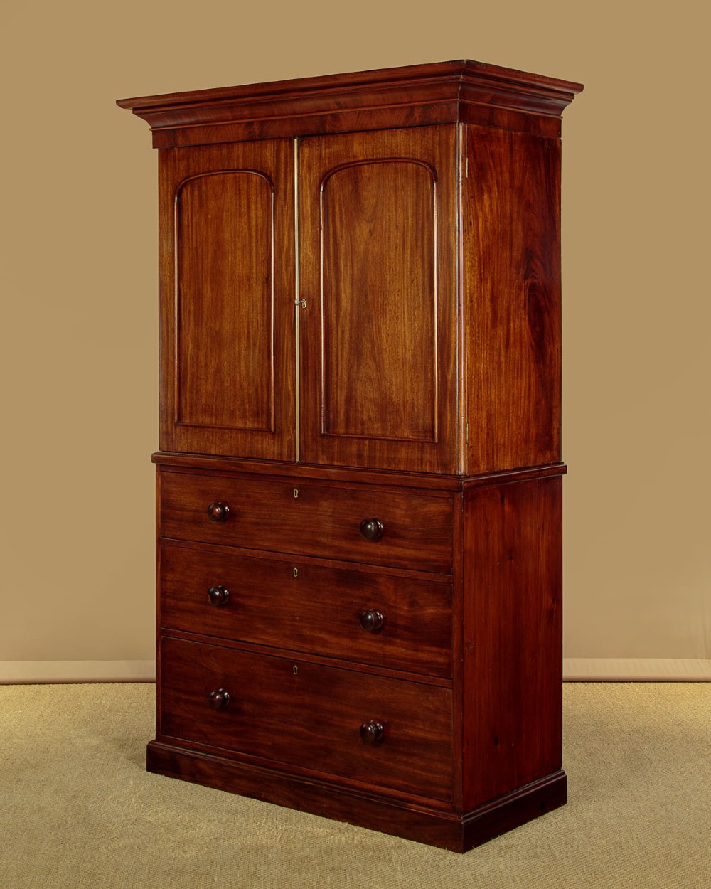A mid-19th century mahogany linen press featuring two arched panel doors over three full-width drawers with turned wooden handles. View III