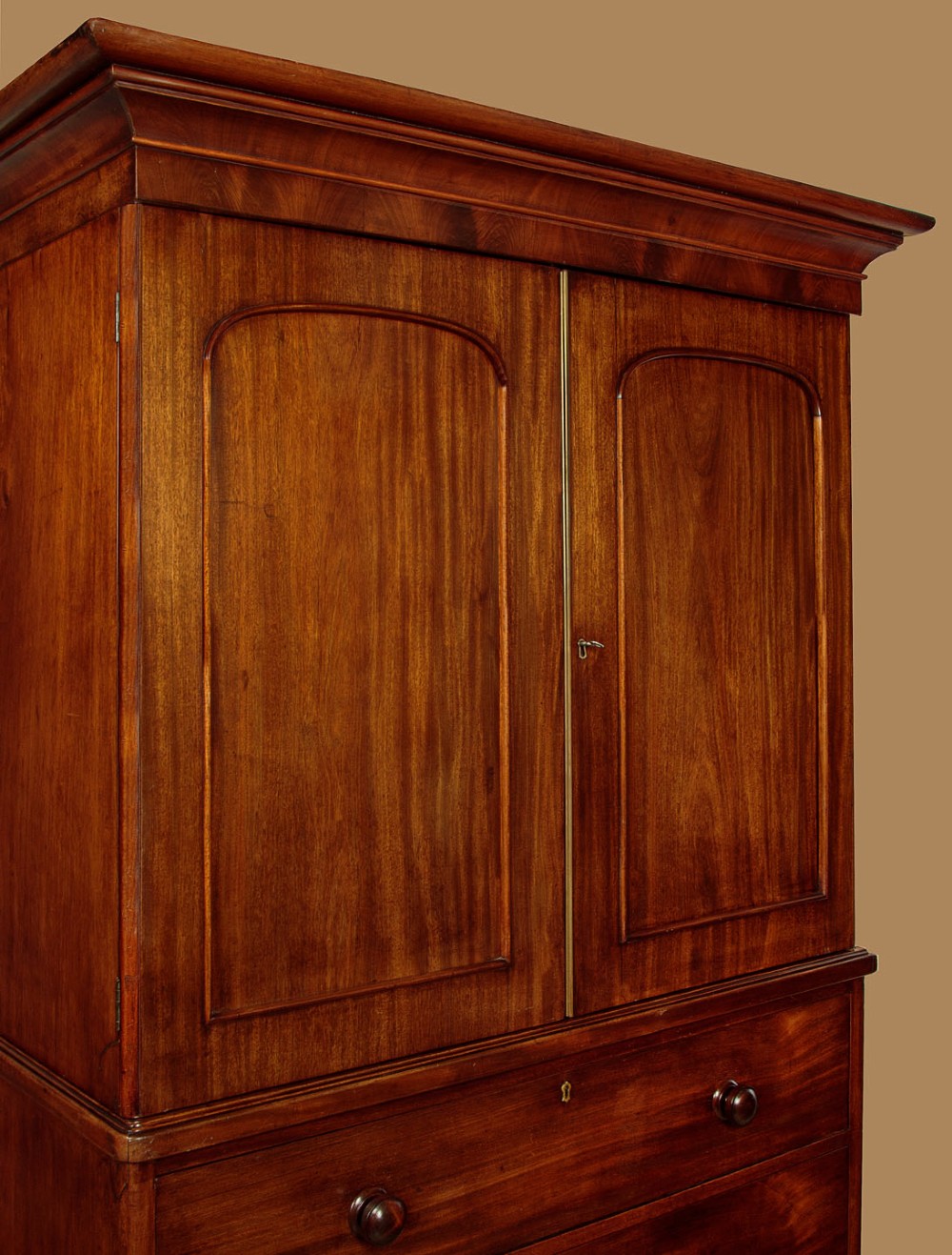 A mid-19th century mahogany linen press featuring two arched panel doors over three full-width drawers with turned wooden handles. View V