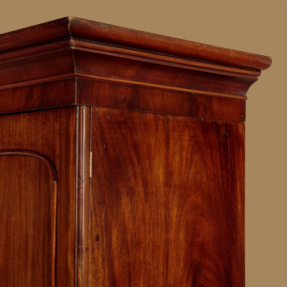 A mid-19th century mahogany linen press featuring two arched panel doors over three full-width drawers with turned wooden handles. View VII