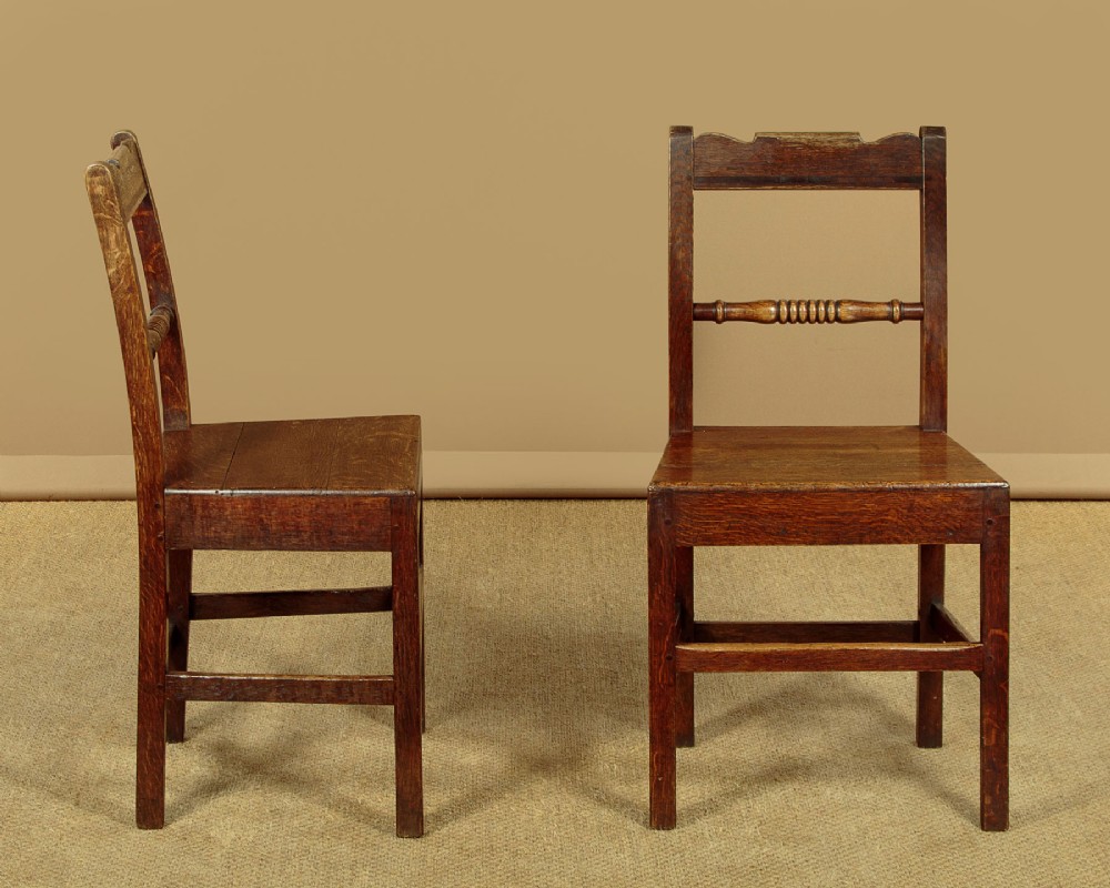A set of four mid-19th-century Welsh oak cottage dining chairs with solid timber seats, turned centre spindles, and square stretchers. View II