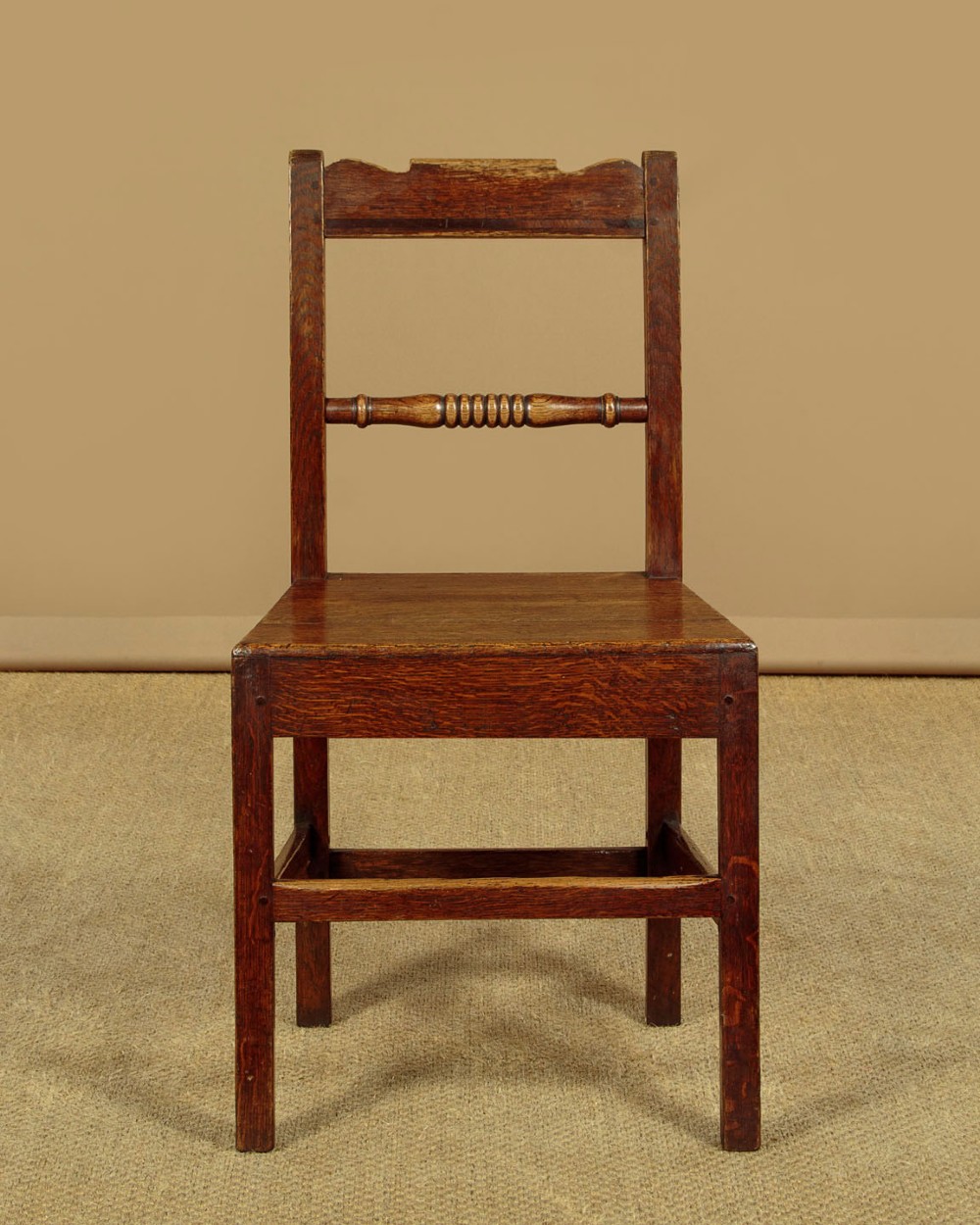 A set of four mid-19th-century Welsh oak cottage dining chairs with solid timber seats, turned centre spindles, and square stretchers. View IV