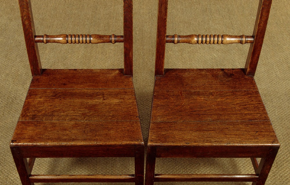 A set of four mid-19th-century Welsh oak cottage dining chairs with solid timber seats, turned centre spindles, and square stretchers. View IX