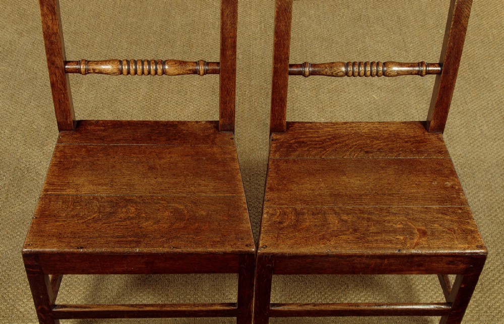A set of four mid-19th-century Welsh oak cottage dining chairs with solid timber seats, turned centre spindles, and square stretchers. View X