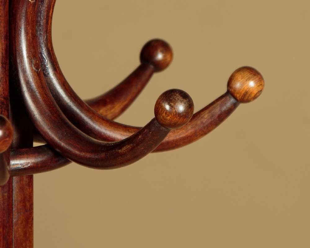 A pair of tall dark brown bentwood hallstands featuring curved coat hooks at the top and circular loops at the base for umbrellas. View VII