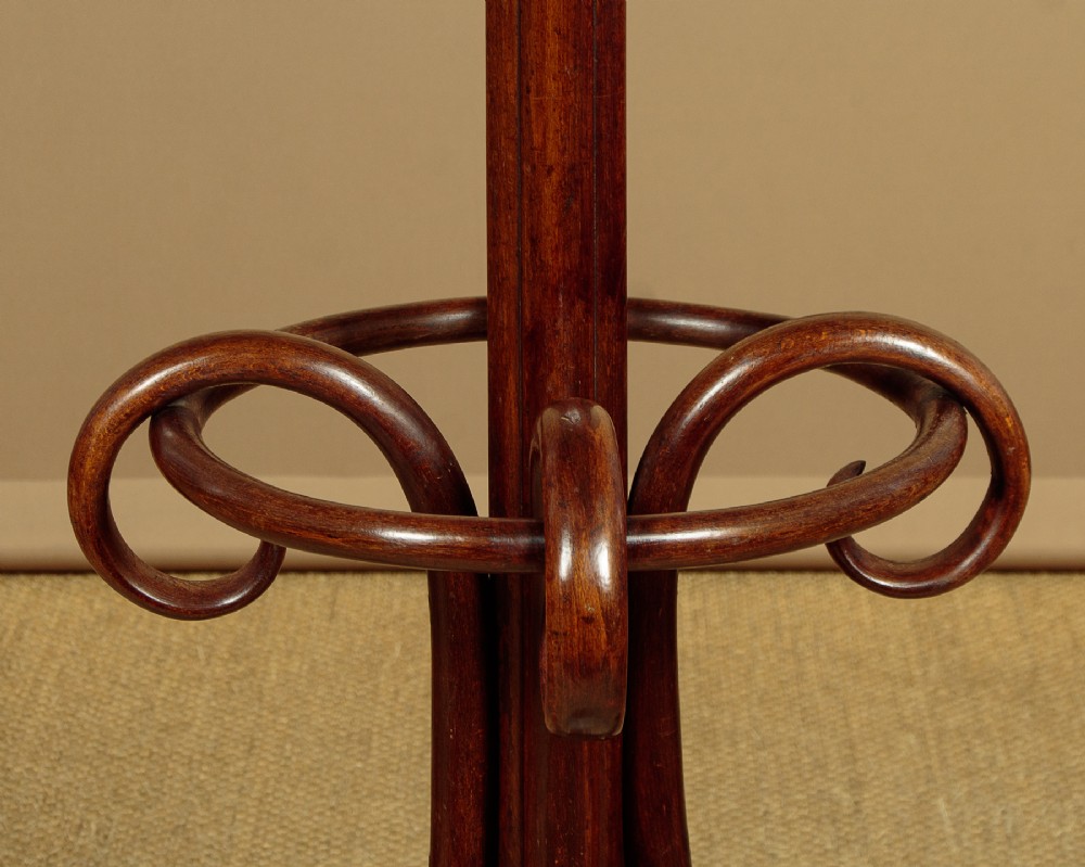 A pair of tall dark brown bentwood hallstands featuring curved coat hooks at the top and circular loops at the base for umbrellas. View VIII