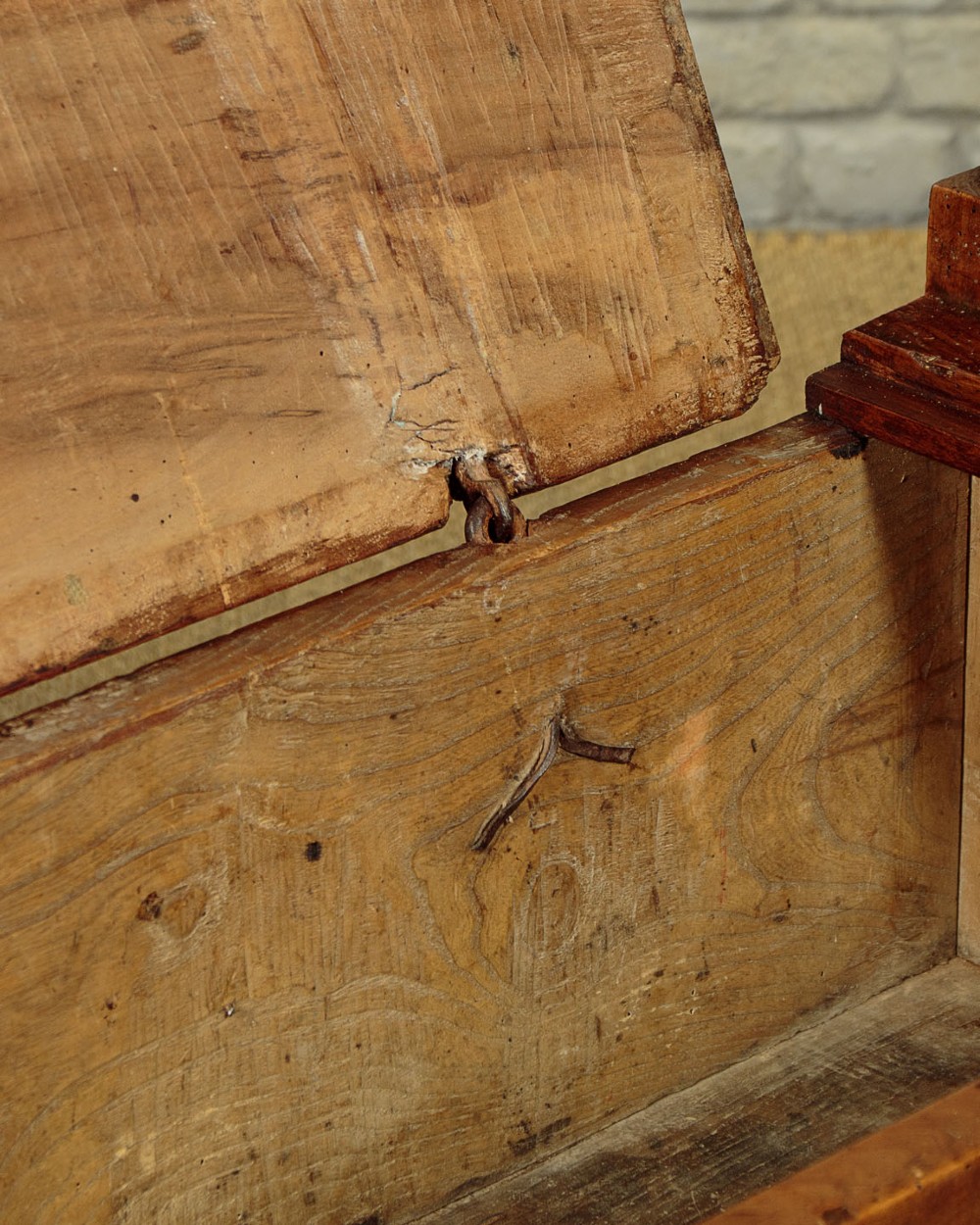 An eighteenth-century warm brown wooden box settle featuring turned end spindles, a hinged lid seat, and an iron keyhole escutcheon. View VIII