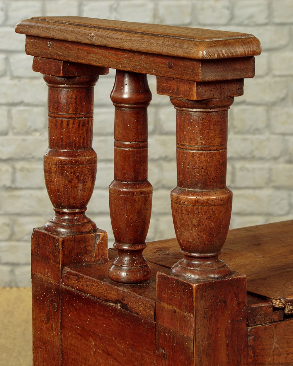 An eighteenth-century warm brown wooden box settle featuring turned end spindles, a hinged lid seat, and an iron keyhole escutcheon. View XI