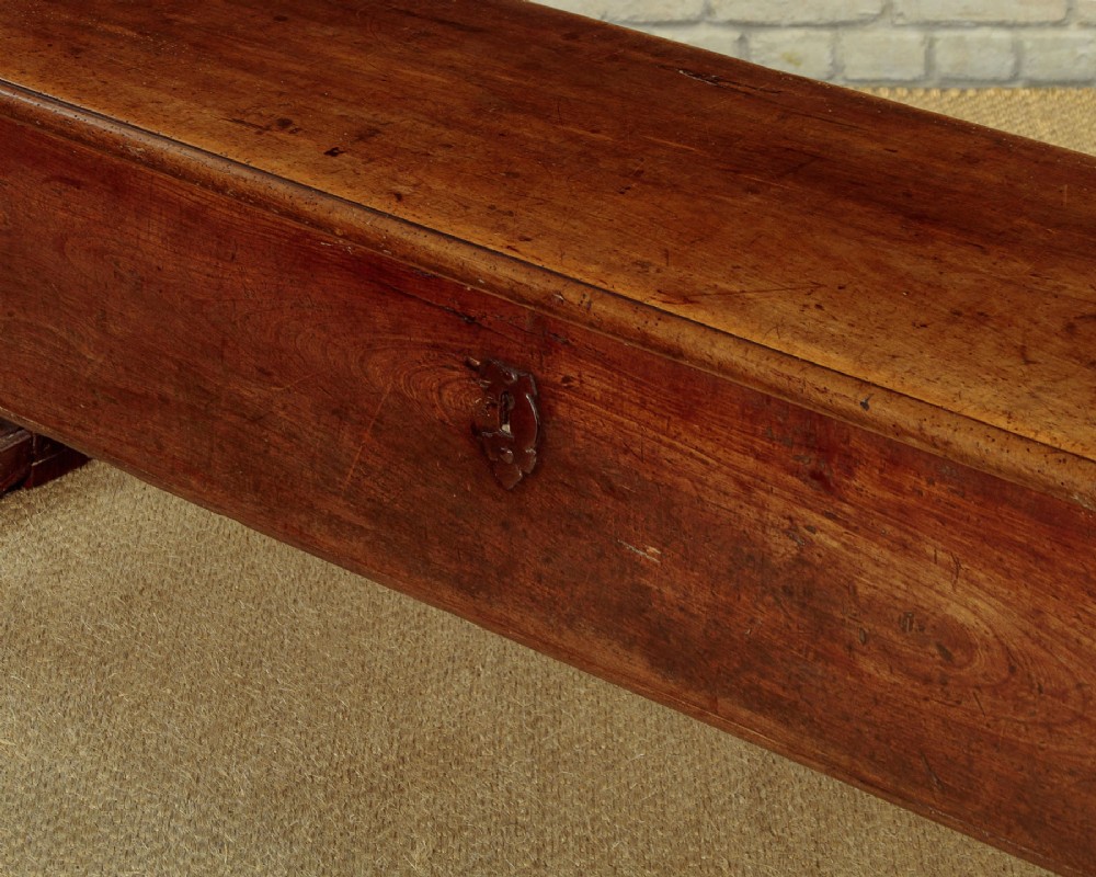 An eighteenth-century warm brown wooden box settle featuring turned end spindles, a hinged lid seat, and an iron keyhole escutcheon. View XII