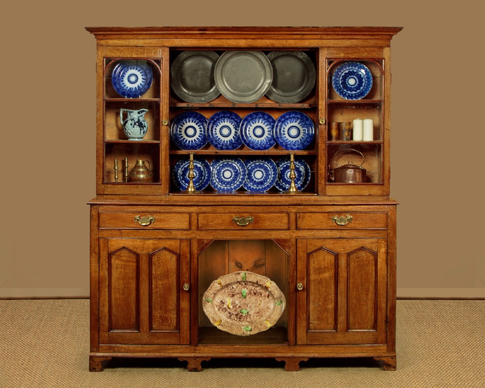 An antique nineteenth-century warm oak Welsh dog kennel dresser featuring an upper rack with glazed side cupboards above a three-drawer base with a central lower alcove. View II
