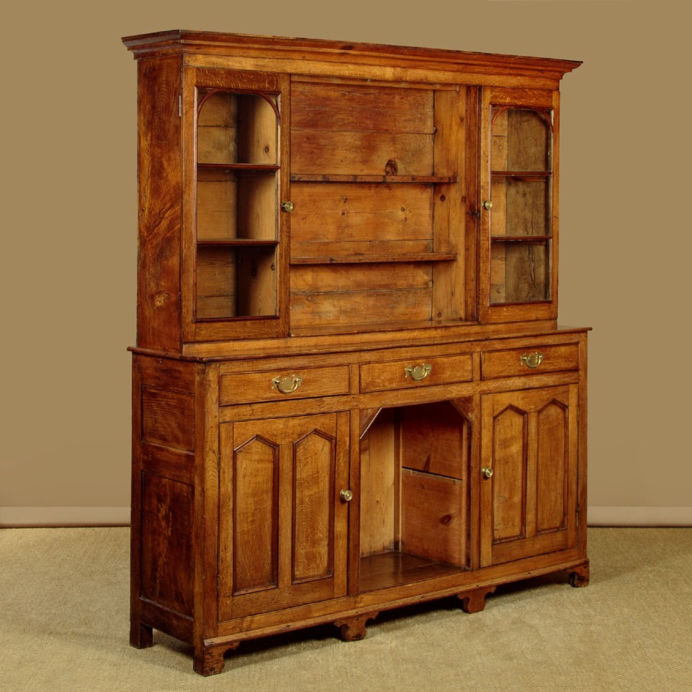 An antique nineteenth-century warm oak Welsh dog kennel dresser featuring an upper rack with glazed side cupboards above a three-drawer base with a central lower alcove. View III