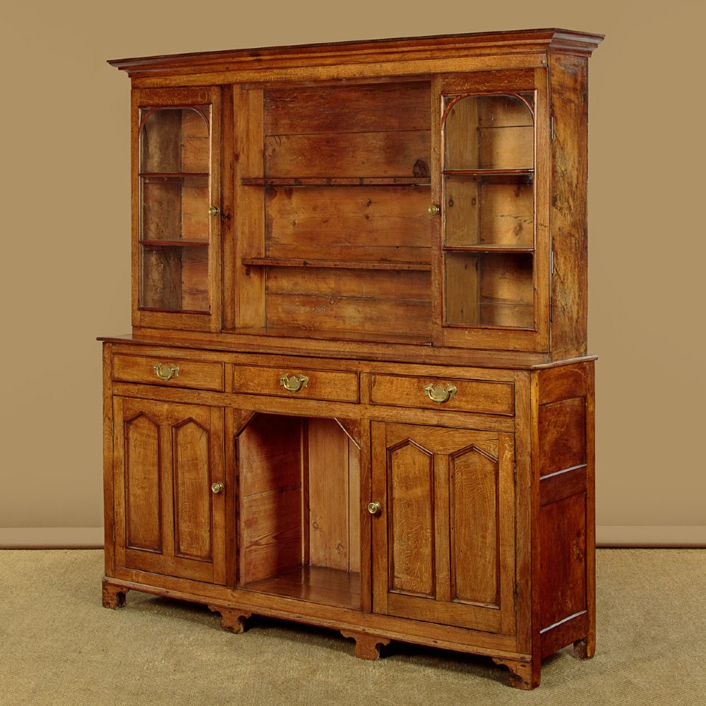 An antique nineteenth-century warm oak Welsh dog kennel dresser featuring an upper rack with glazed side cupboards above a three-drawer base with a central lower alcove. View IV