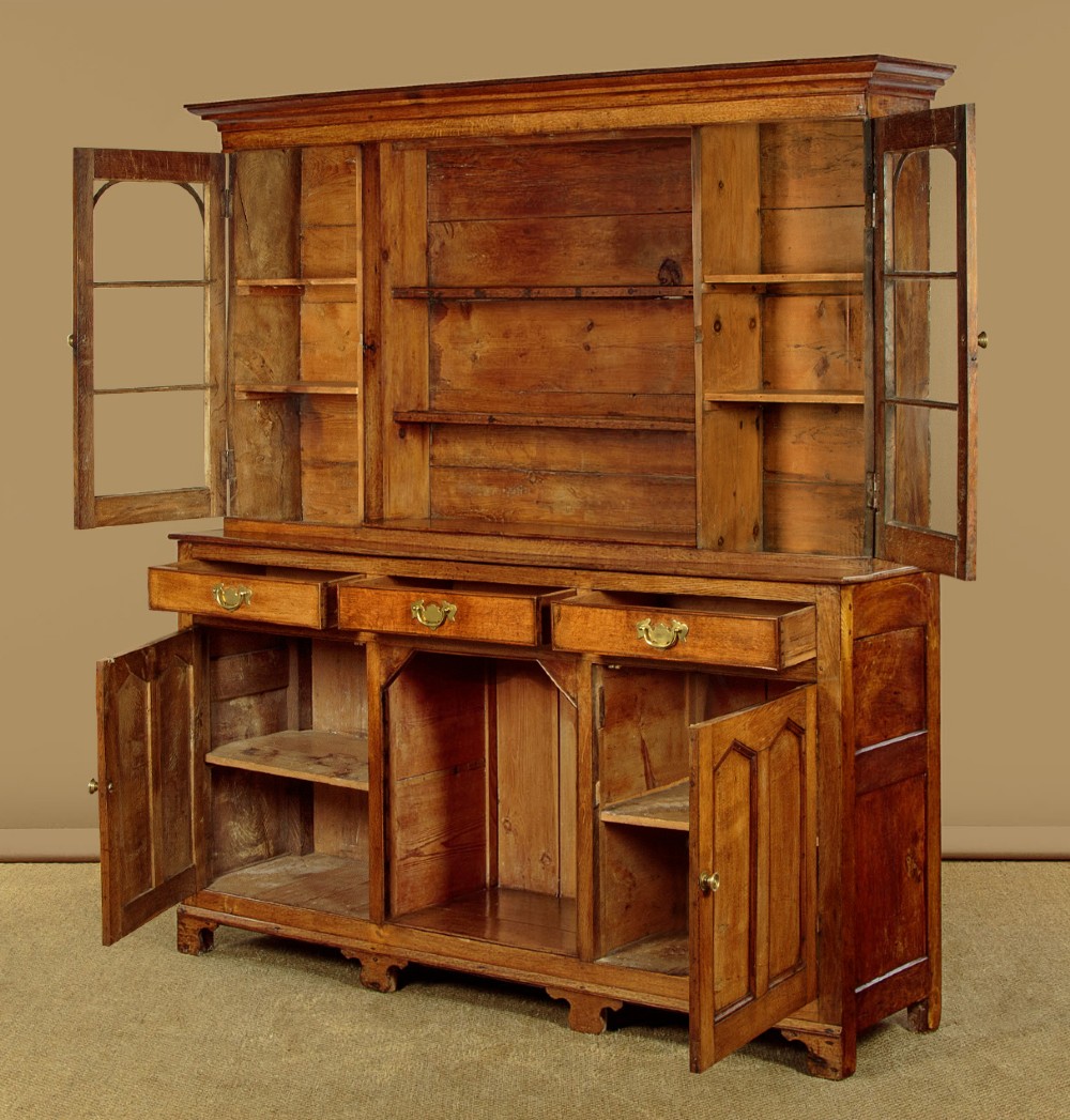 An antique nineteenth-century warm oak Welsh dog kennel dresser featuring an upper rack with glazed side cupboards above a three-drawer base with a central lower alcove. View V