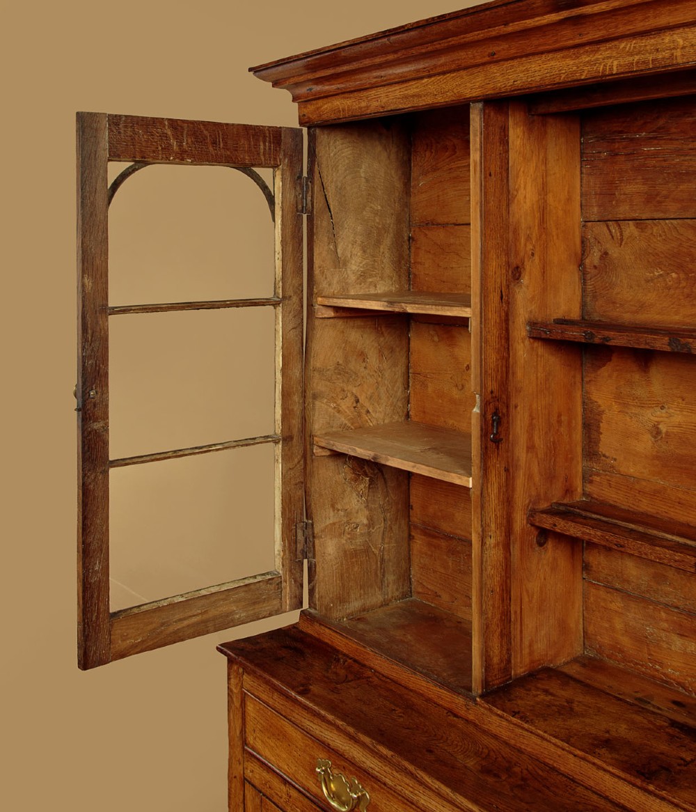 An antique nineteenth-century warm oak Welsh dog kennel dresser featuring an upper rack with glazed side cupboards above a three-drawer base with a central lower alcove. View VIII
