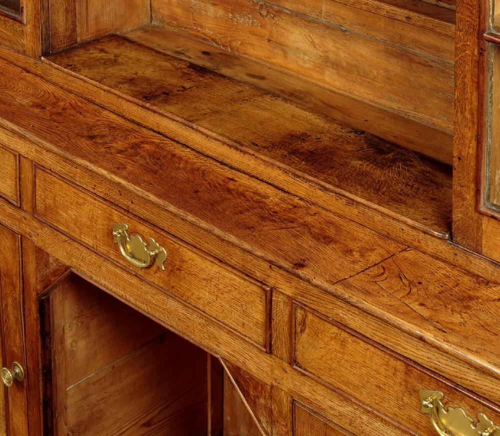 An antique nineteenth-century warm oak Welsh dog kennel dresser featuring an upper rack with glazed side cupboards above a three-drawer base with a central lower alcove. View XI