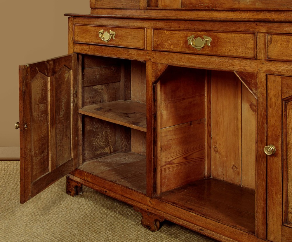 An antique nineteenth-century warm oak Welsh dog kennel dresser featuring an upper rack with glazed side cupboards above a three-drawer base with a central lower alcove. View XIV
