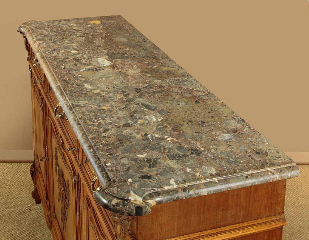 A French walnut sideboard featuring three top drawers, three panelled cabinet doors with central carved fruit motifs, brass handles, cabriole legs, and a fitted dark marble top. View V