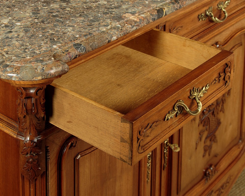A French walnut sideboard featuring three top drawers, three panelled cabinet doors with central carved fruit motifs, brass handles, cabriole legs, and a fitted dark marble top. View IX