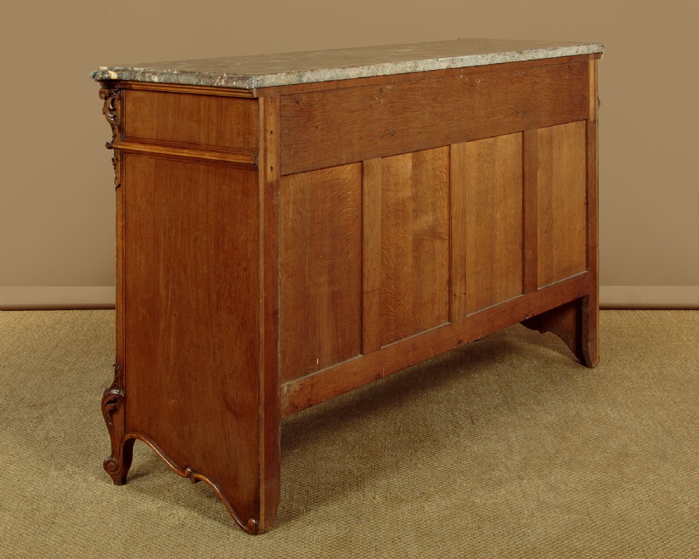 A French walnut sideboard featuring three top drawers, three panelled cabinet doors with central carved fruit motifs, brass handles, cabriole legs, and a fitted dark marble top. View XV