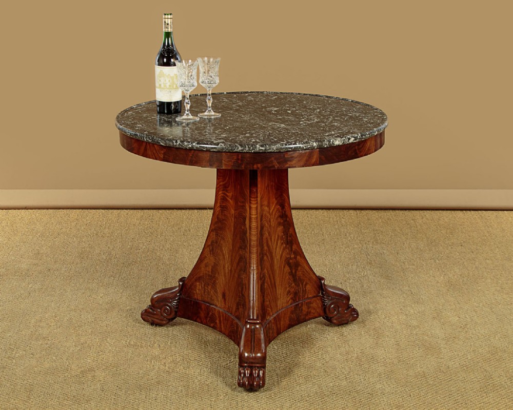 A circular antique mahogany gueridon centre table featuring a dark grey marble top, a flared central pedestal, and carved paw feet. View II