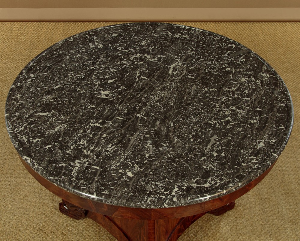 A circular antique mahogany gueridon centre table featuring a dark grey marble top, a flared central pedestal, and carved paw feet. View III