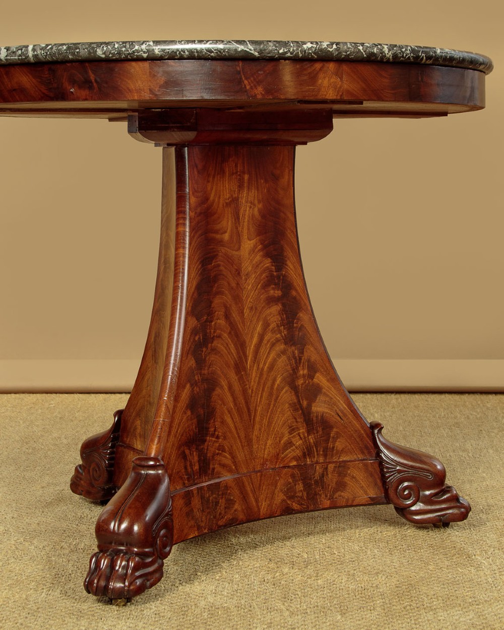 A circular antique mahogany gueridon centre table featuring a dark grey marble top, a flared central pedestal, and carved paw feet. View VII