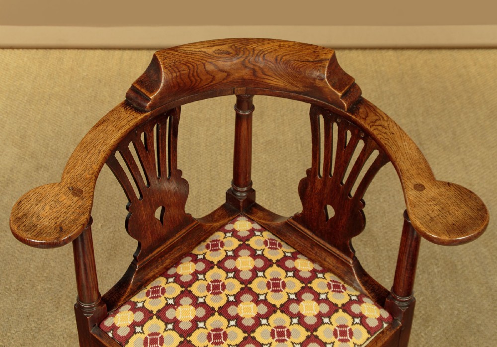 An eighteenth-century dark oak corner armchair featuring a curved top rail, two pierced splats, a patterned drop-in seat, and a central cabriole front leg. View IV