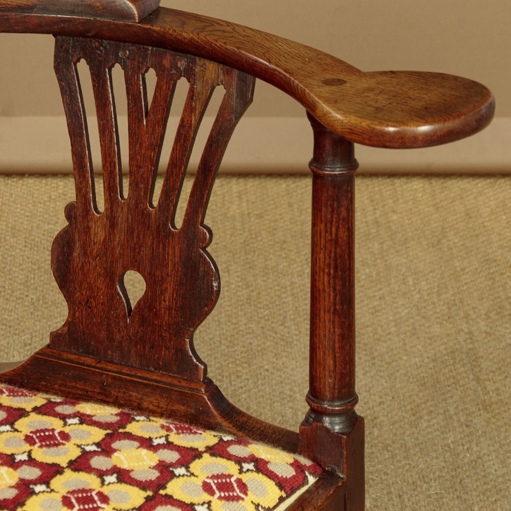 An eighteenth-century dark oak corner armchair featuring a curved top rail, two pierced splats, a patterned drop-in seat, and a central cabriole front leg. View VI