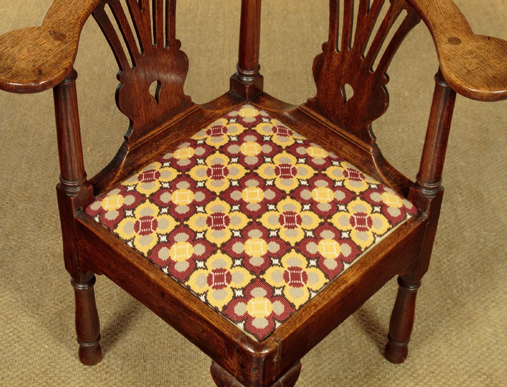 An eighteenth-century dark oak corner armchair featuring a curved top rail, two pierced splats, a patterned drop-in seat, and a central cabriole front leg. View VII