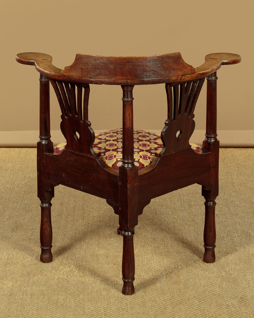 An eighteenth-century dark oak corner armchair featuring a curved top rail, two pierced splats, a patterned drop-in seat, and a central cabriole front leg. View X