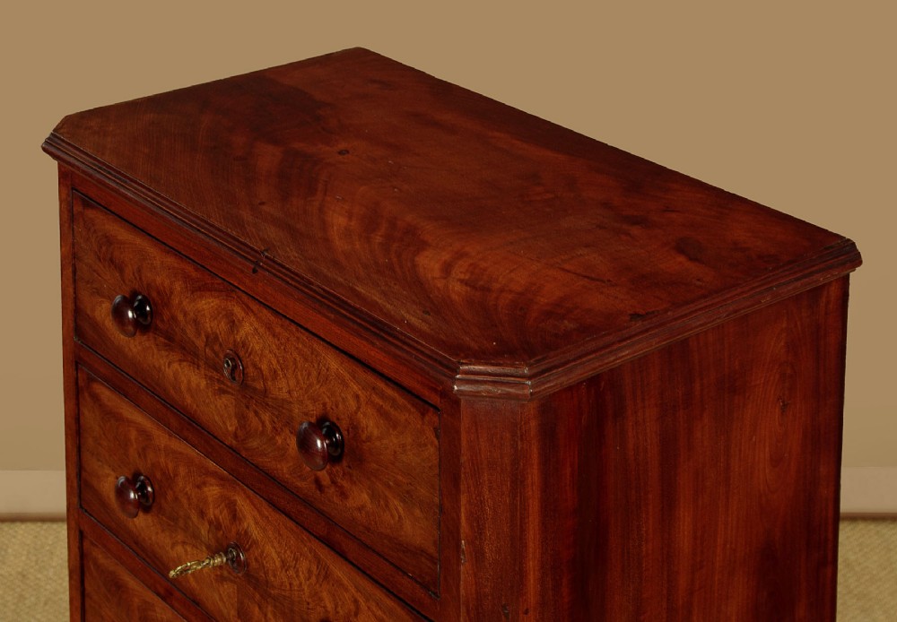 A tall and narrow Victorian mahogany bank of seven graduated drawers featuring flame mahogany veneer fronts, turned wood knob handles, and a solid plinth base. View V