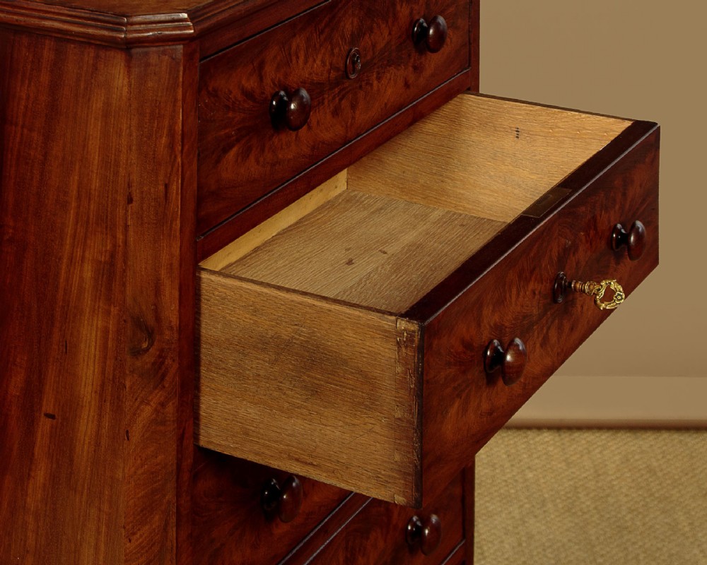 A tall and narrow Victorian mahogany bank of seven graduated drawers featuring flame mahogany veneer fronts, turned wood knob handles, and a solid plinth base. View VII