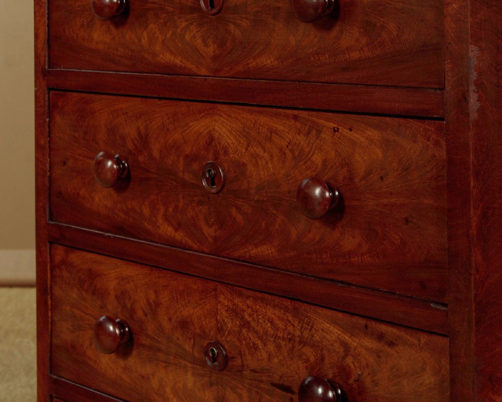 A tall and narrow Victorian mahogany bank of seven graduated drawers featuring flame mahogany veneer fronts, turned wood knob handles, and a solid plinth base. View VIII