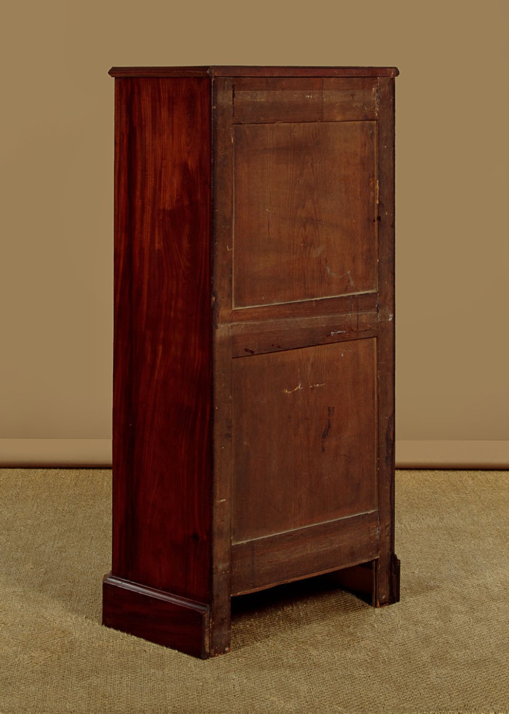 A tall and narrow Victorian mahogany bank of seven graduated drawers featuring flame mahogany veneer fronts, turned wood knob handles, and a solid plinth base. View X