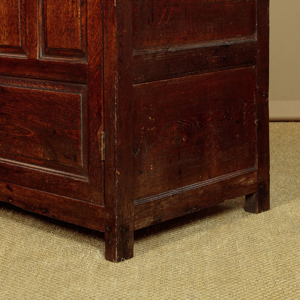 An 18th-century dark Welsh oak cwpwrdd deuddarn featuring an overhanging canopy with drop pendants, upper fielded panel doors, two drawers, and lower cupboard doors. View XII
