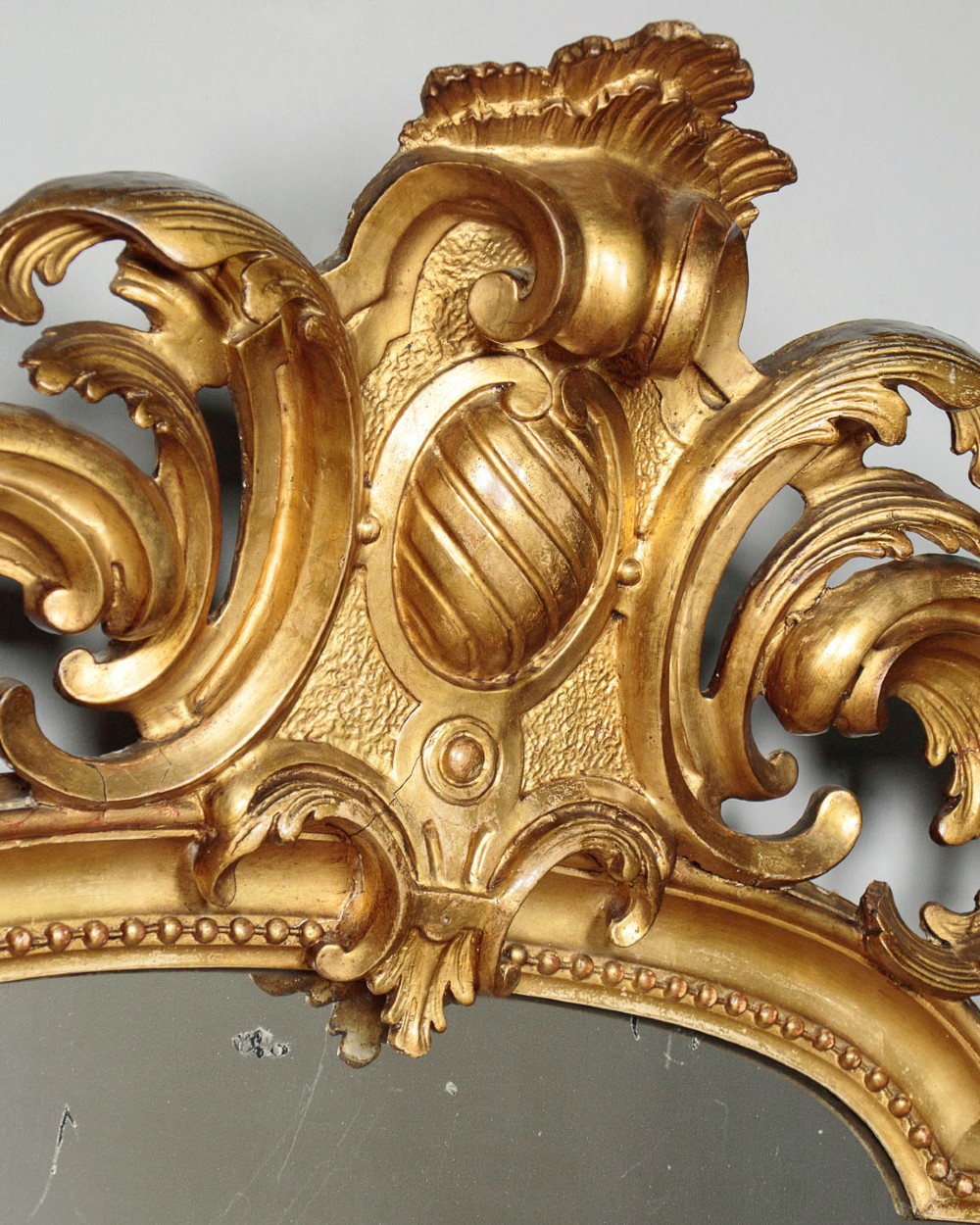 A large late Victorian giltwood overmantel mirror with an arched top, detailed beaded inner rim, and carved cresting featuring acanthus scrollwork. View IV