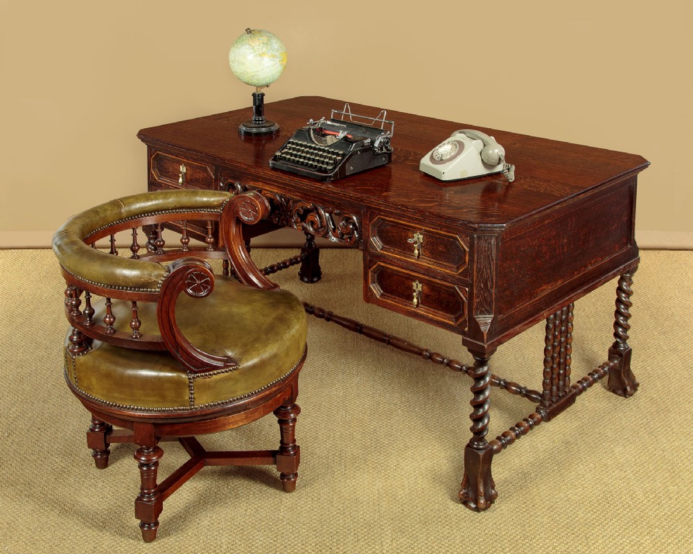 A dark carved oak writing desk featuring four geometric drawers, a scroll-carved central frieze, barley-twist legs, and a stretcher base. View II