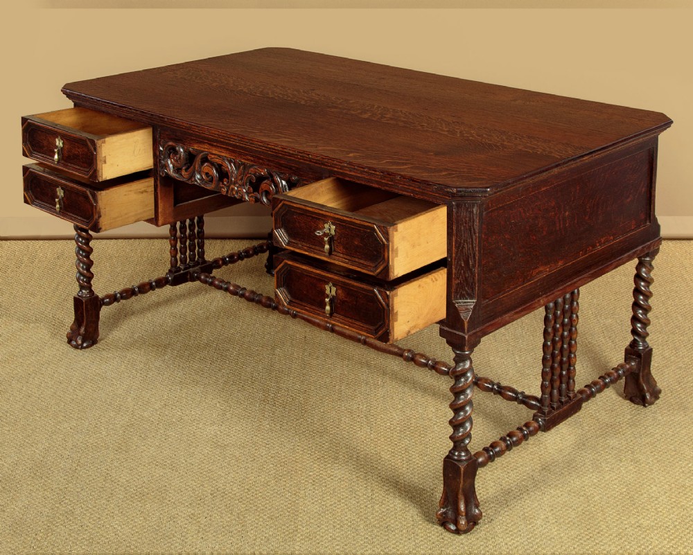 A dark carved oak writing desk featuring four geometric drawers, a scroll-carved central frieze, barley-twist legs, and a stretcher base. View V