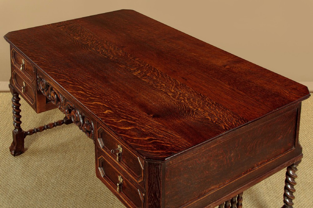 A dark carved oak writing desk featuring four geometric drawers, a scroll-carved central frieze, barley-twist legs, and a stretcher base. View VI