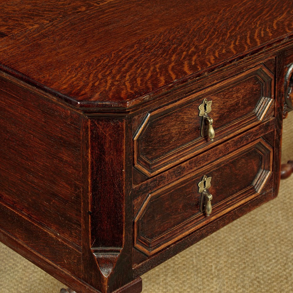 A dark carved oak writing desk featuring four geometric drawers, a scroll-carved central frieze, barley-twist legs, and a stretcher base. View VII