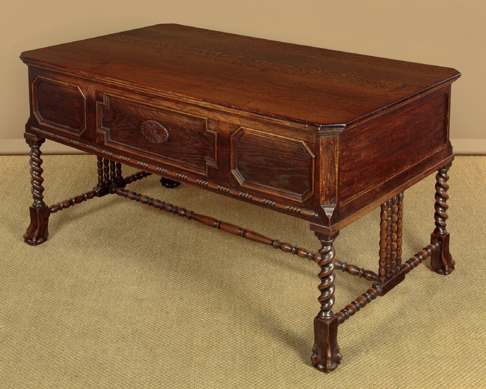 A dark carved oak writing desk featuring four geometric drawers, a scroll-carved central frieze, barley-twist legs, and a stretcher base. View XII