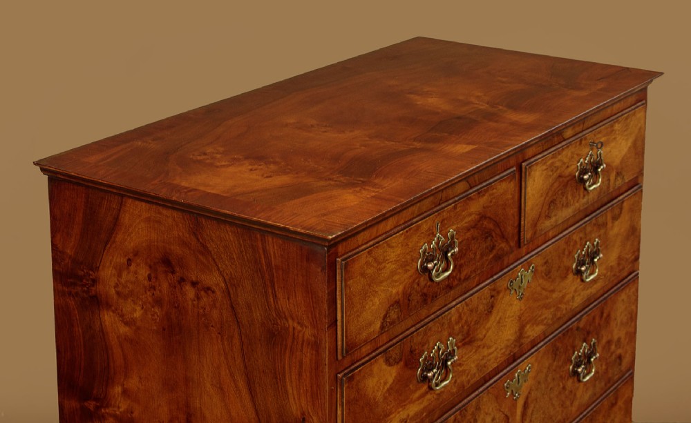 A 1930s Queen Anne Revival burr walnut chest on stand featuring multiple graduated drawers, decorative brass handles, turned legs, and a shaped apron. View V