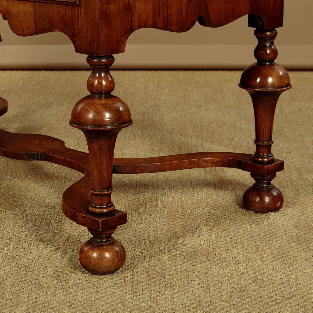 A 1930s Queen Anne Revival burr walnut chest on stand featuring multiple graduated drawers, decorative brass handles, turned legs, and a shaped apron. View IX