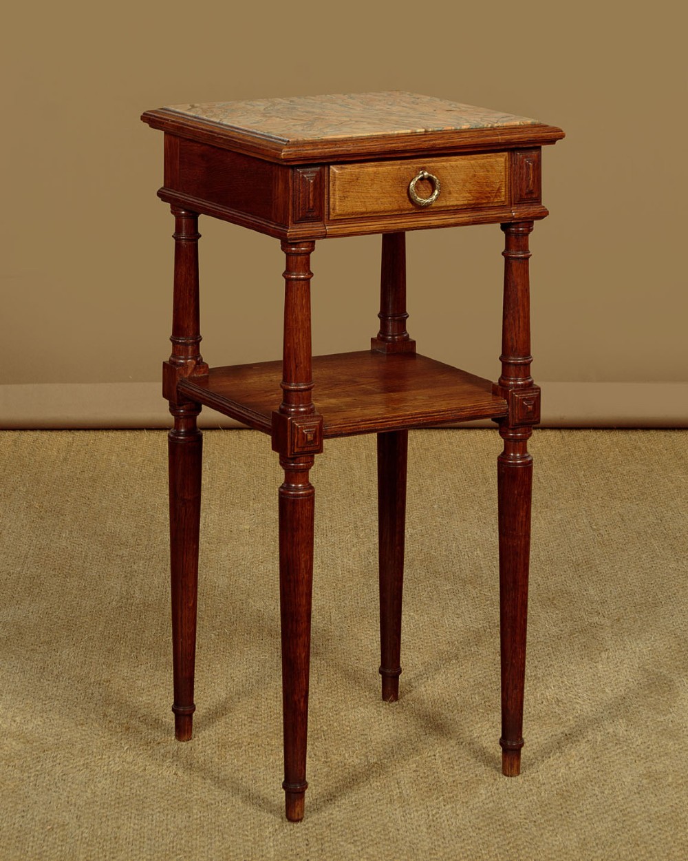A pair of slender Edwardian oak lamp tables featuring inset marble tops, single drawers with brass ring pulls, turned tapered legs, and lower tier shelves. View IV
