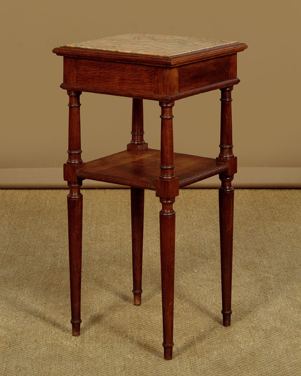 A pair of slender Edwardian oak lamp tables featuring inset marble tops, single drawers with brass ring pulls, turned tapered legs, and lower tier shelves. View XIV