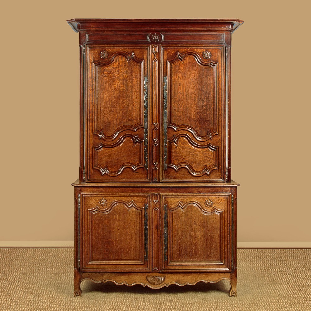 An 18th-century French provincial oak housekeepers cupboard featuring two upper and two lower moulded panel doors with carved star motifs and cabriole feet.