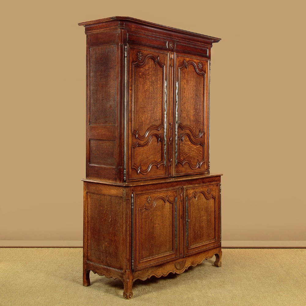 An 18th-century French provincial oak housekeepers cupboard featuring two upper and two lower moulded panel doors with carved star motifs and cabriole feet. View II