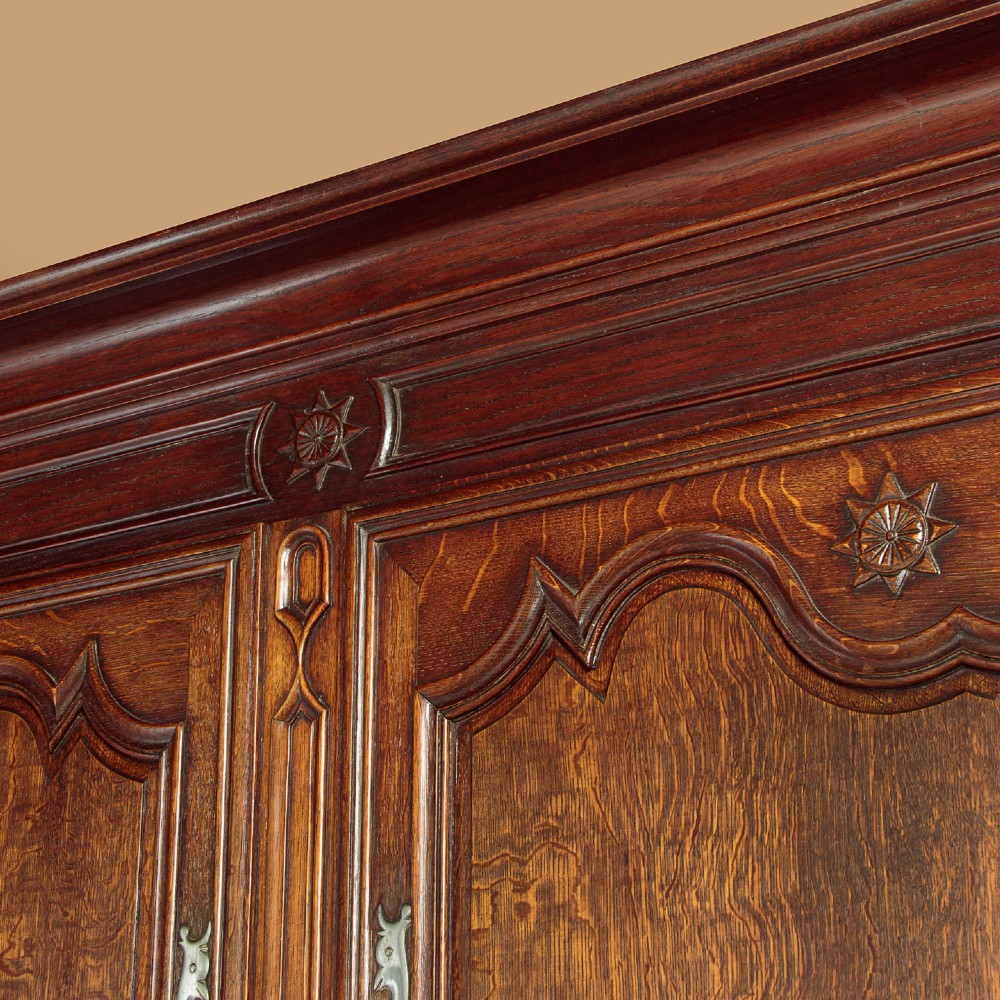 An 18th-century French provincial oak housekeepers cupboard featuring two upper and two lower moulded panel doors with carved star motifs and cabriole feet. View V