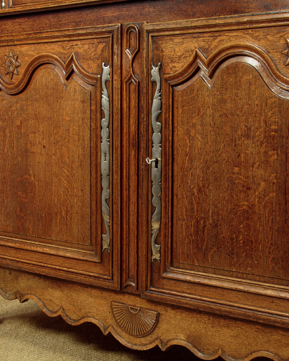 An 18th-century French provincial oak housekeepers cupboard featuring two upper and two lower moulded panel doors with carved star motifs and cabriole feet. View IX